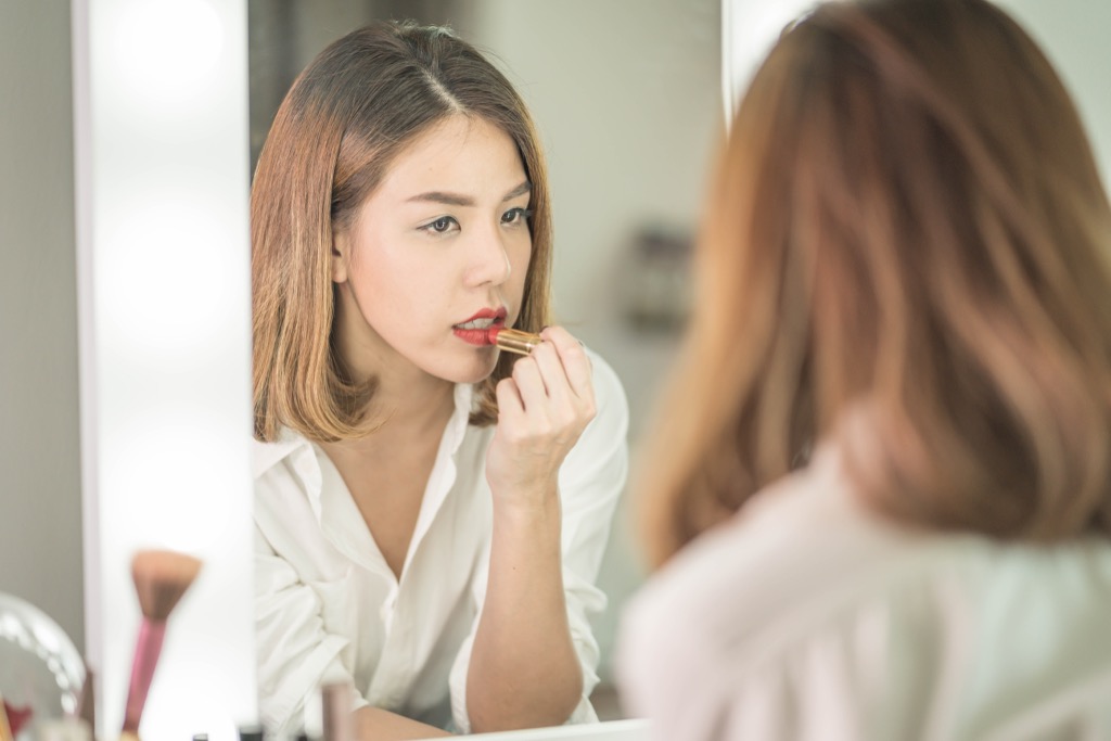 woman applying lipstick in a mirror