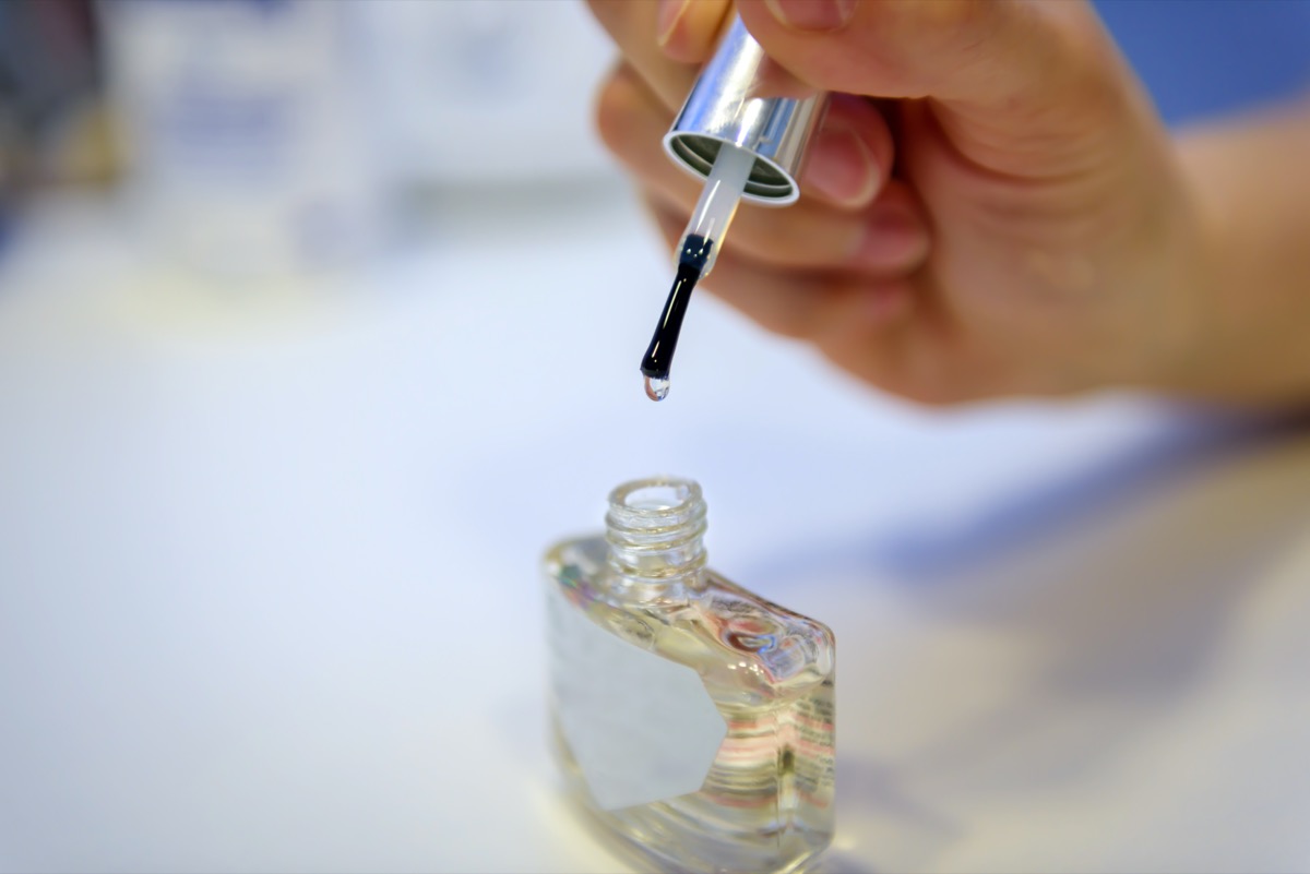 white hand holding clear nail polish