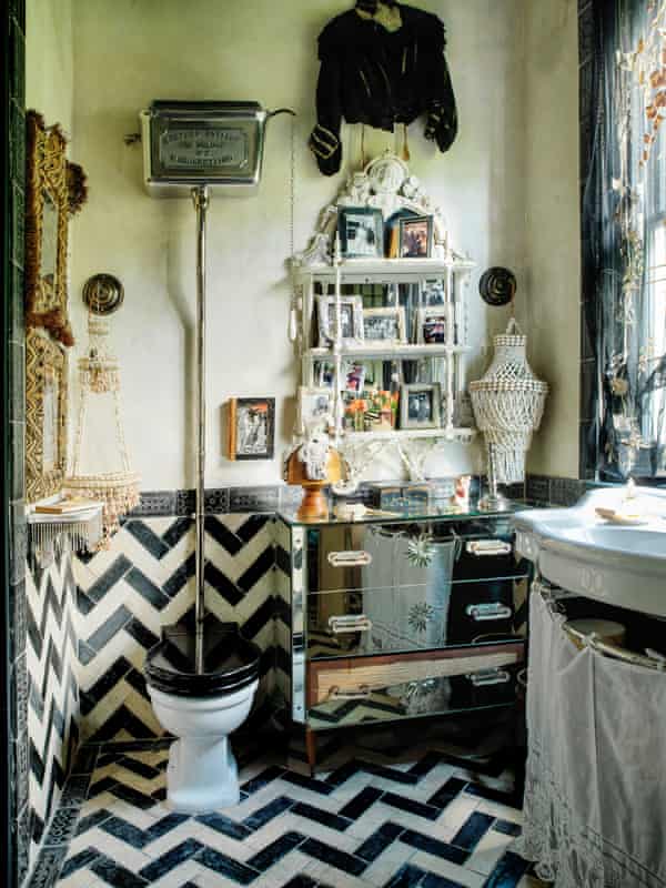 A bathroom with black and white zigzag floor tiles, and anitque furniture