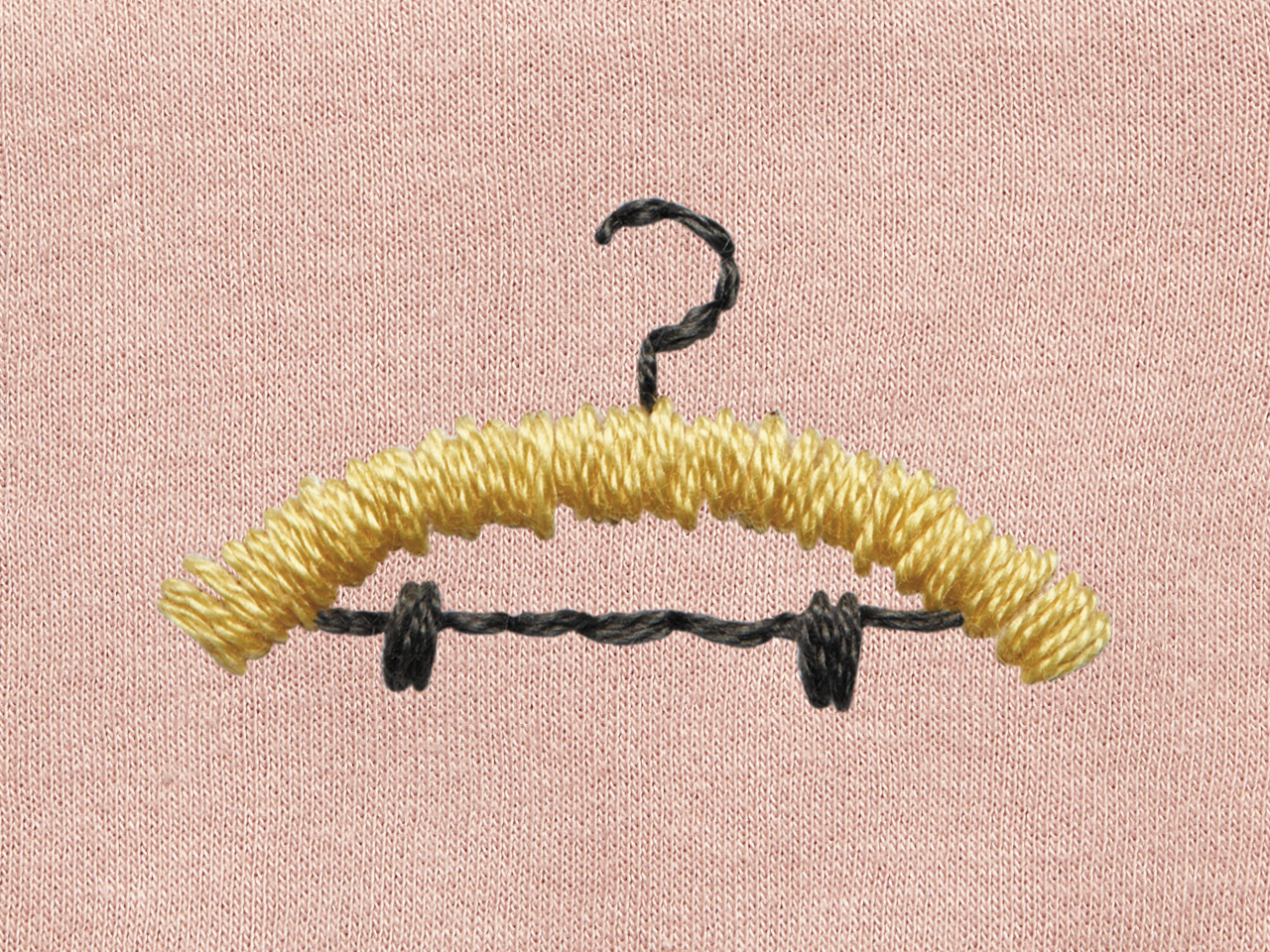 An embroidered yellow hanger on a pink cloth background