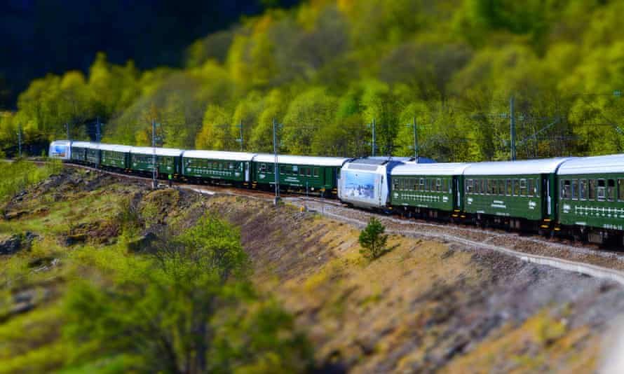A Flåm Railway train running through a valley, in Norway.