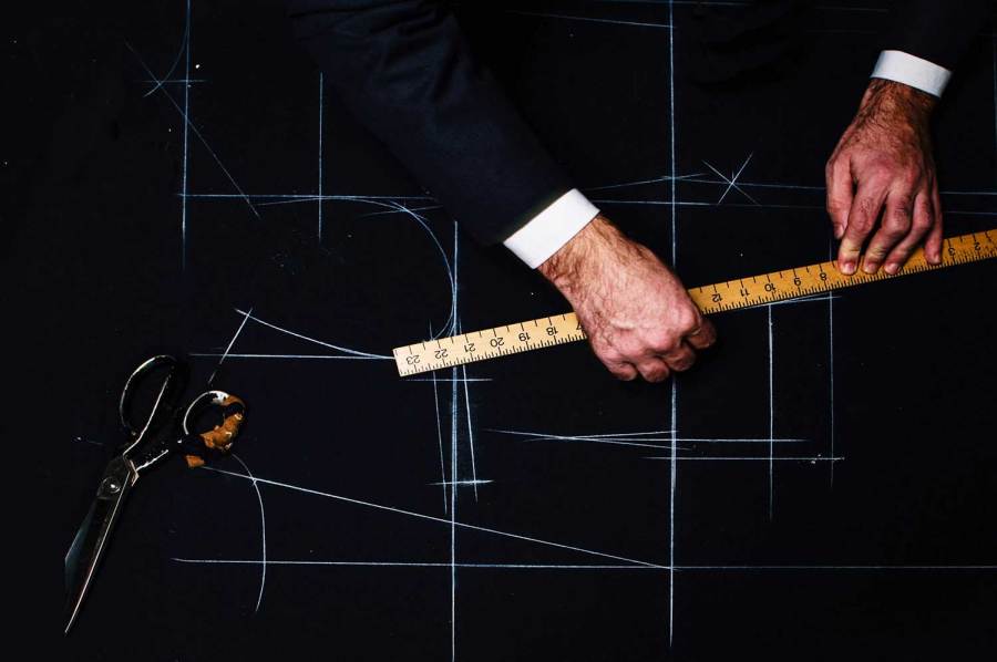 A tailor measures a pattern for a made to measure suit