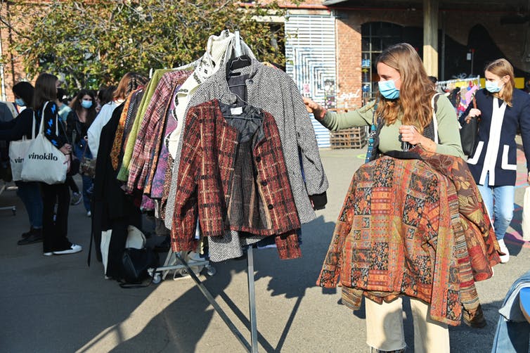 Person browses second hand clothes at market