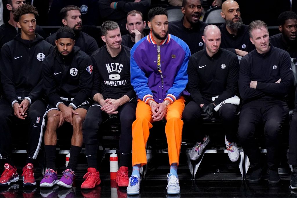 Ben Simmons sitting courtside at a basketball game, brooklyn nets and celtics game, outfit orange pants, purple jacket, nba 2022 finals