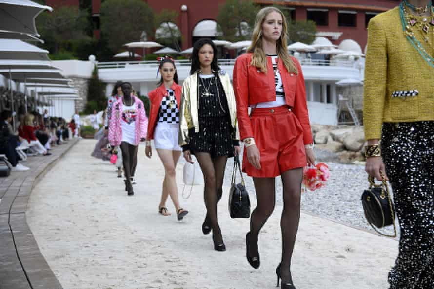 Row of models walking down beachfront catwalk.