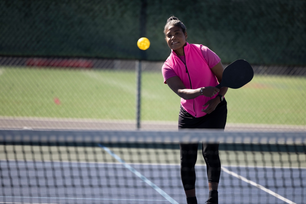 A woman enjoying playing pickle ball in the sunshine.