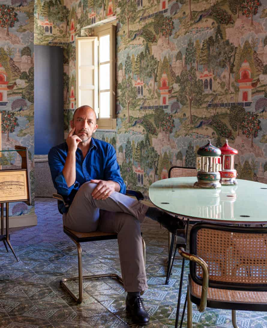 Owner Dario Longo sitting at a modern table with a fresco wall behind him