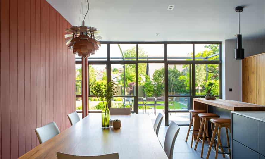 The dining table in the kitchen looks out through a wall of glass doors to the garden