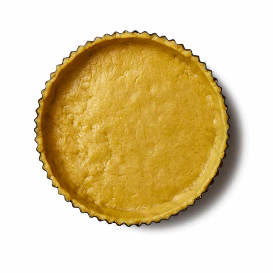 Unfold the pastry into the tin, and press rather than stretch it so it sits flush with the right angle between the base and the sides and then trim. Then you want to fill with baking beans and “blind bake”.