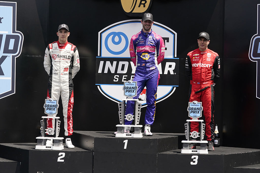 Alexander Rossi, middle, poses with the trophy after winning IndyCar auto race at Indianapolis Motor Speedway, Saturday, July 30, 2022, in Indianapolis. Christian Lundgard, left, of Denmark, finished second and Will Power, of Autralia finished third. 