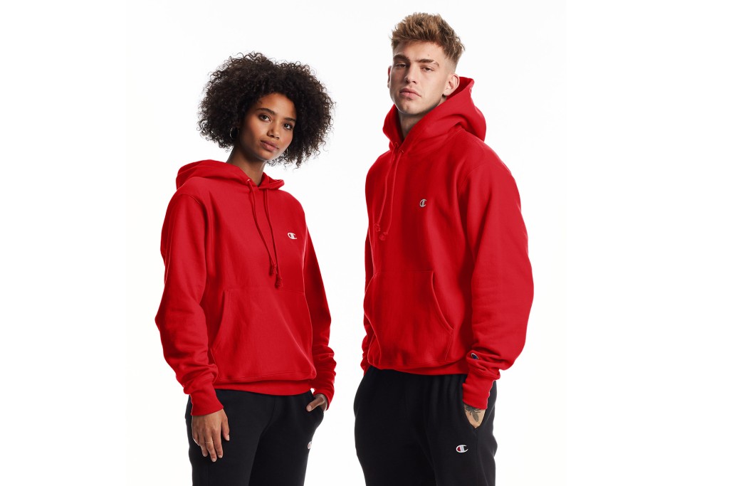 A man and a woman wear matching red Champion brand hoodies 