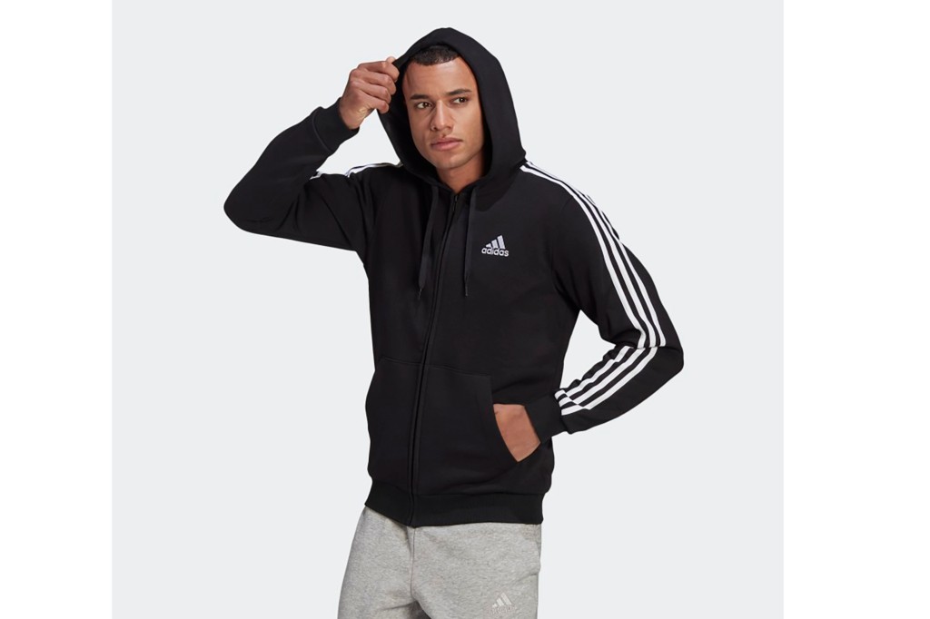 A man in a black Adidas hoodie with white stripes down the sleeves 