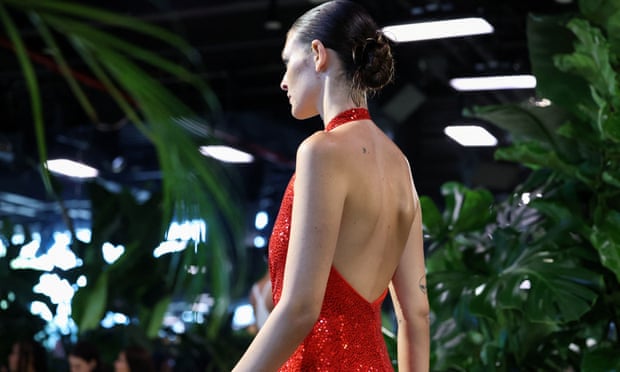 A model wearing a red sequined dress walks the runway for Michael Kors’ Spring 2023 show. 