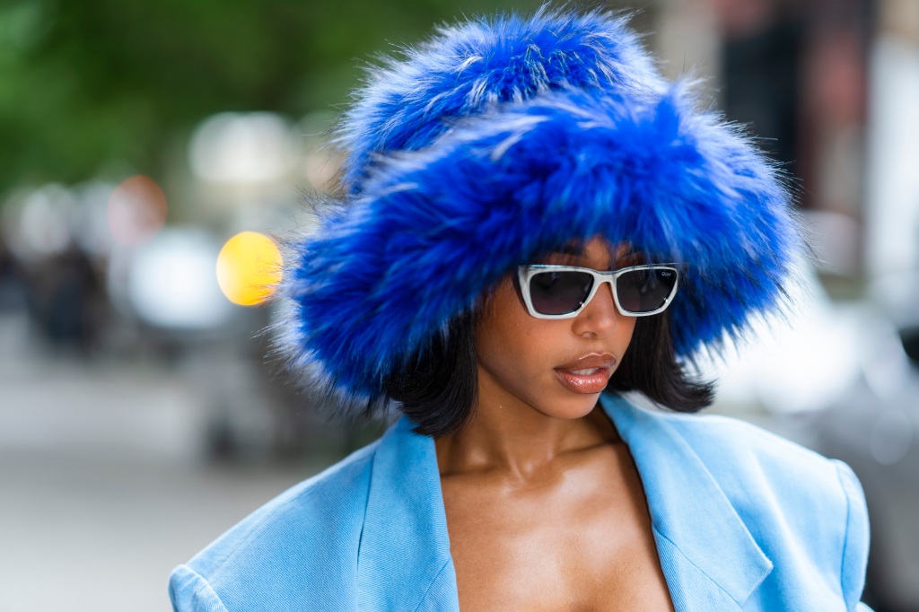 Lori Harvey walks through the streets of New York City in a blue and white outfit, with a giant fluffy bucket hat.