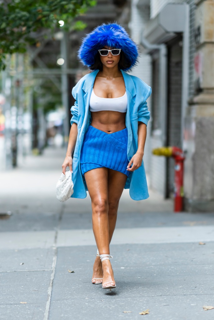 Lori Harvey walks through the streets of New York City in a blue and white outfit, with a giant fluffy bucket hat.