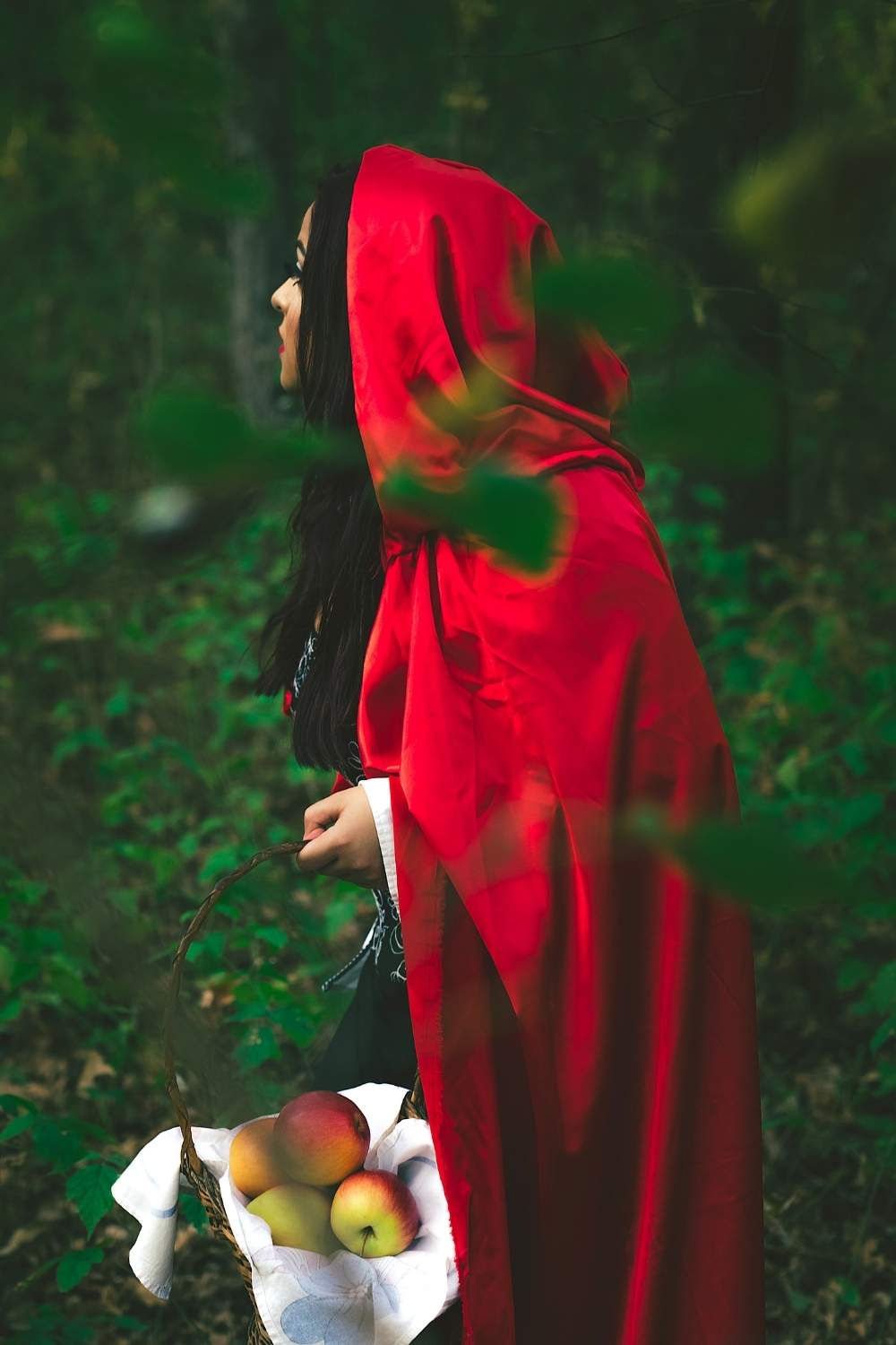 Woman wears red cape and carries a basket of apples, as a DIY Halloween costume.