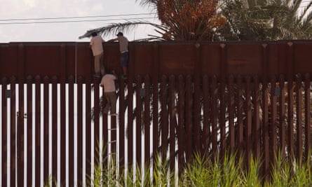 Migrants use a rope ladder to illegally climb over the US-Mexico border wall in El Centro, California.