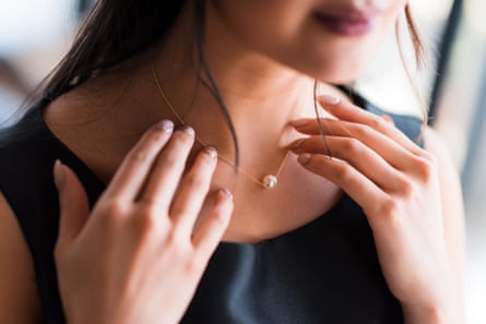 Close-up of a woman’s neck as she tries on a necklace