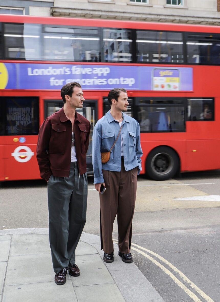 Two men standing on the street in front of a double decker bus