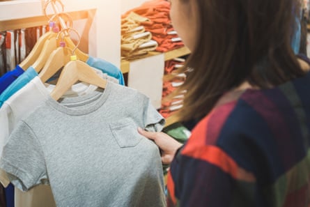 Midsection Of woman inspecting T-shirt while standing at store
