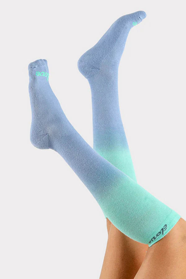 Close up of raised legs wearing green and blue compression socks from charity brand Clove.