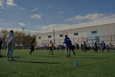 An Amazon warehouse is seen behind Red Hook ball fields during a youth football practice.