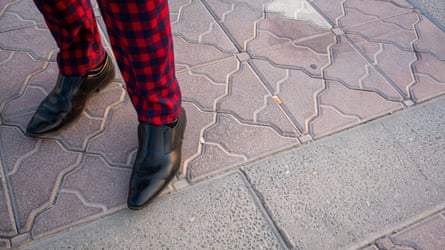 Close-up image of a man wearing red-and-black checked trousers and black pointed shoes on the Corniche in Doha, Qatar.