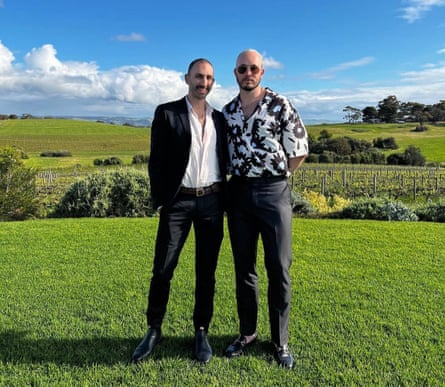 Two men in smart clothes pose in a countryside setting