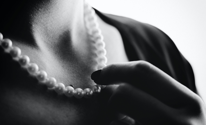 why pearls are so special woman touching pearl necklace on her neck black and white unsplash