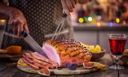 Person slicing roasted ham.