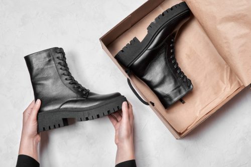 Woman holding black leather women's lug sole boots in box 