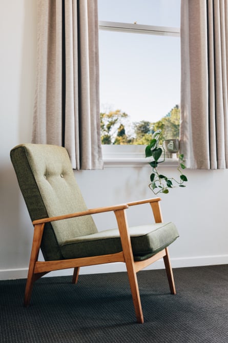 A olive-green lounge chair by a window framed by grey curtains