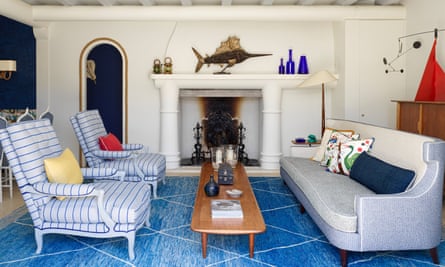 The nautical-themed living room, with blue carpet, blue sofa and two blue and white chairs.