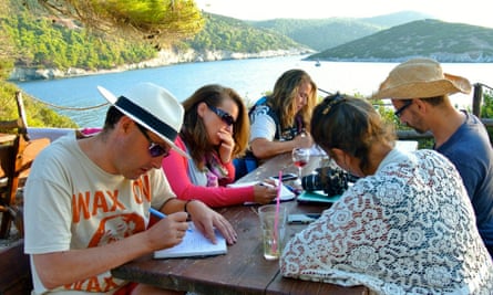 people writing at a waterside table