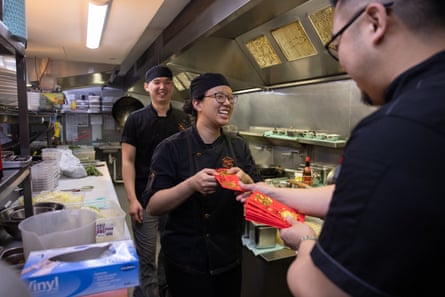In a restaurant kitchen, a staff member receives a lucky red packet of money from their employer for lunar new year.