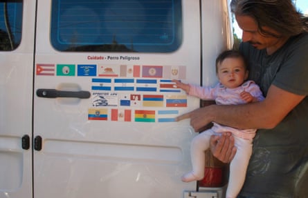 man and baby outside van with decals of many different flags