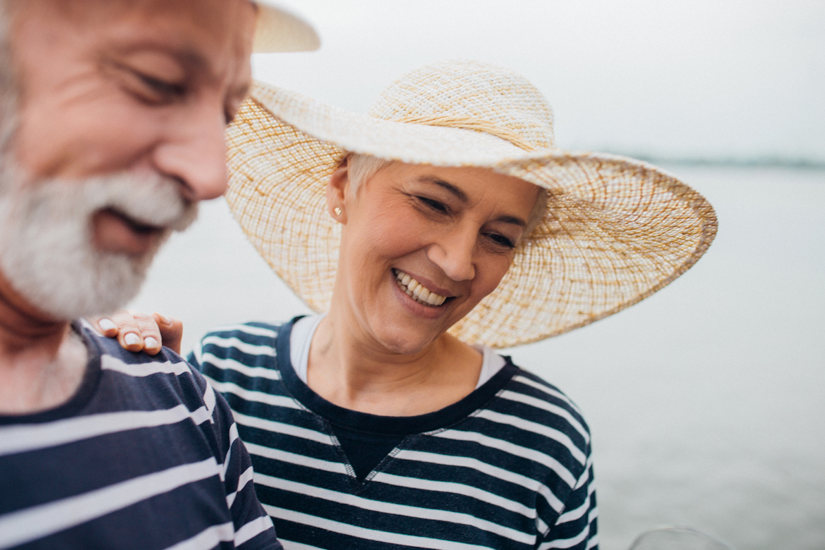 Happy senior couple wearing matching navy blue and white striped shirts and hats.