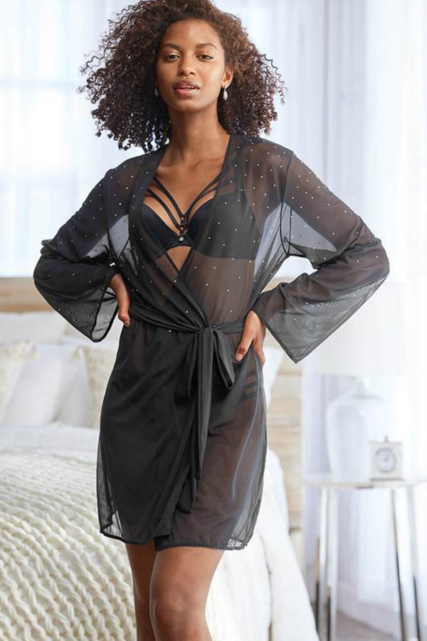 Model wears sheer black robe with rhinestones.