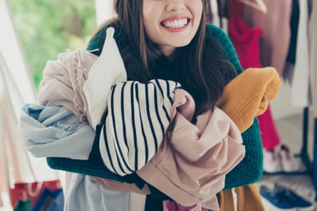 A woman smiling while holding a bundle of clothes in her arms.