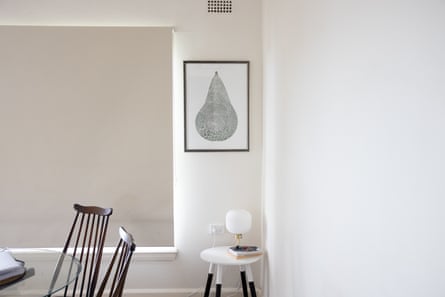 A framed black-and-white lino print of a pear in a white-walled living room.