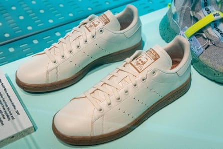 A pair of white leather-look lace-up sneakers on a turquoise blue surface.