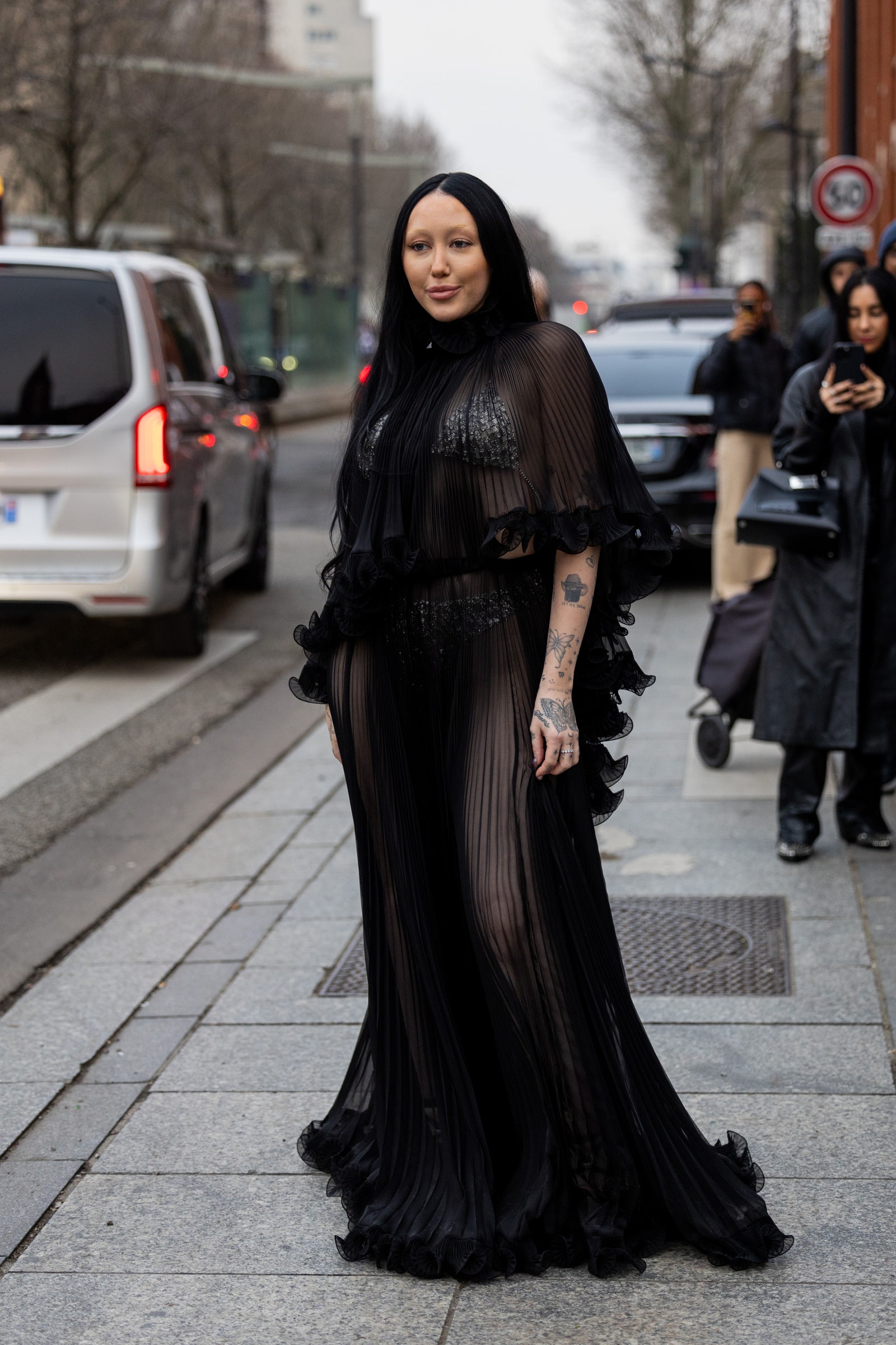 Noah Cyrus wears black pleated see trough dress outside Alexandre Vauthier during Paris Fashion Week.
