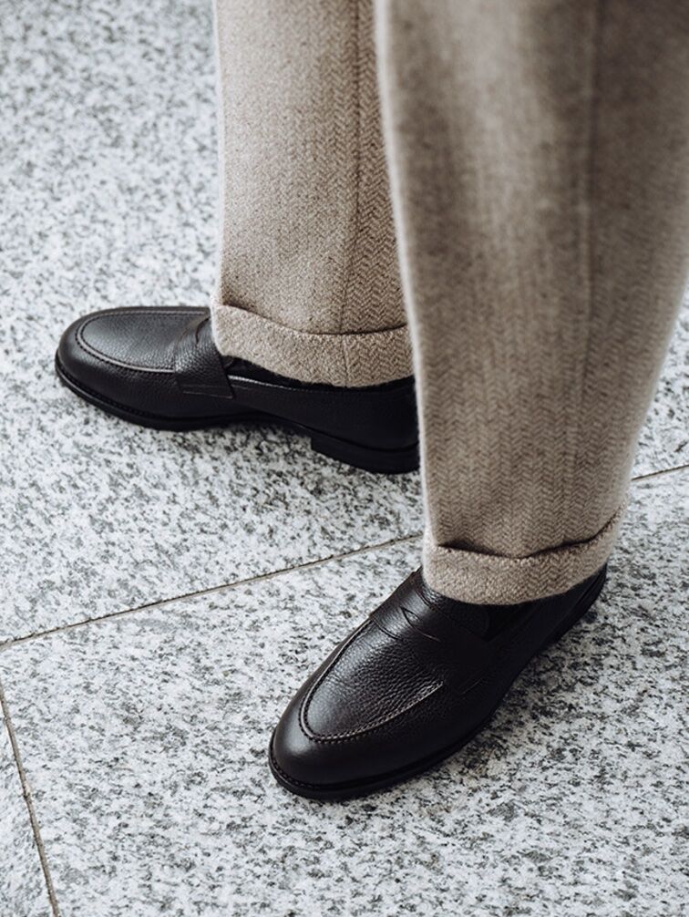 Below the knee shot of tailored trousers and leather penny loafers