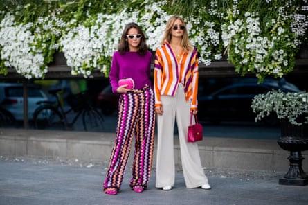 Guests wearing purple knit, multi colored wide leg pants, pink clutch and a guest wearing striped button shirt, wide leg pants, red Chanel bag  during Stockholm Runway SS19.