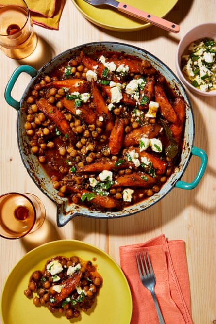 A large casserole dish with a braise of chickpeas, tomatoes and carrots, studded with feta and sprinkled with herbs.