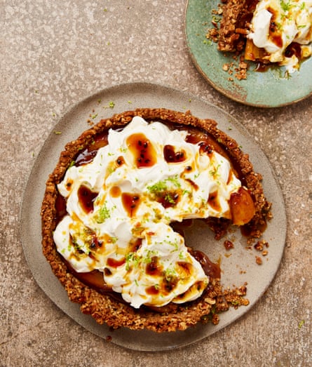 Overhead shot of a crusty pie filled with caramel bananas and topped with whipped cream, caramel and lime zest.