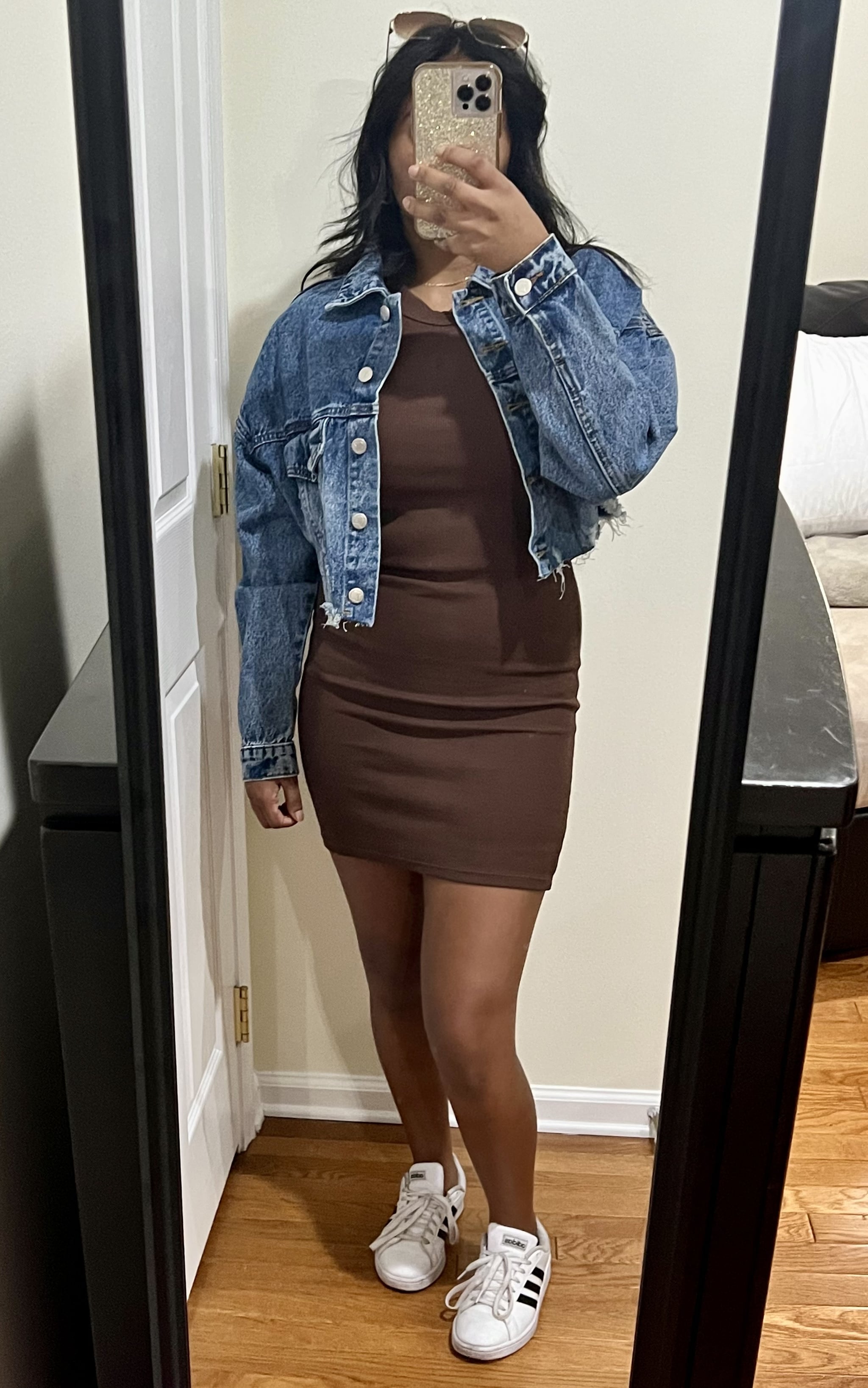 Woman wearing the Old Navy Fitted Sleeveless Rib-Knit Mini Dress in Peppercorn brown with a jean jacket and sneakers.