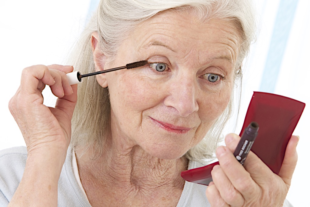 older woman applying makeup, look better after 40