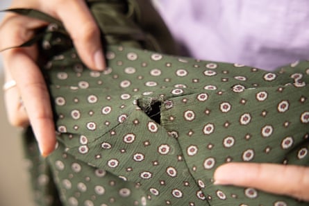 Close up of a hole in a dark green polyester top