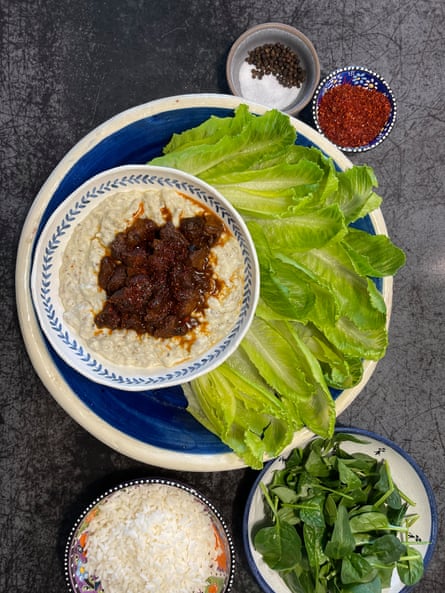 A bowl of lamb stew and of smooth eggplant puree, surrounded by baby cos lettuce leaves. 